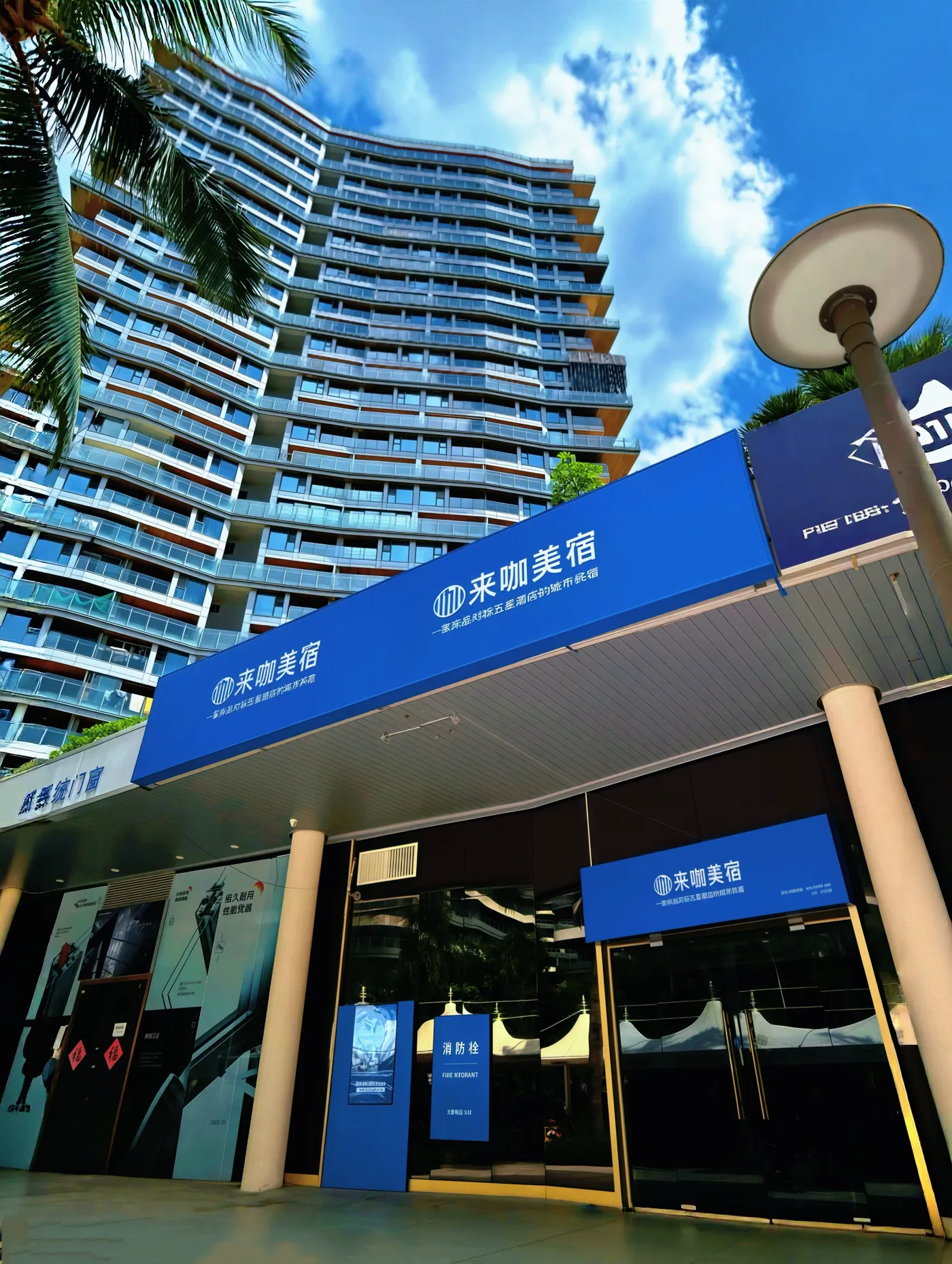 来咖美宿半山半岛店 门店门头实拍，蓝色来咖美宿招牌与小区入口