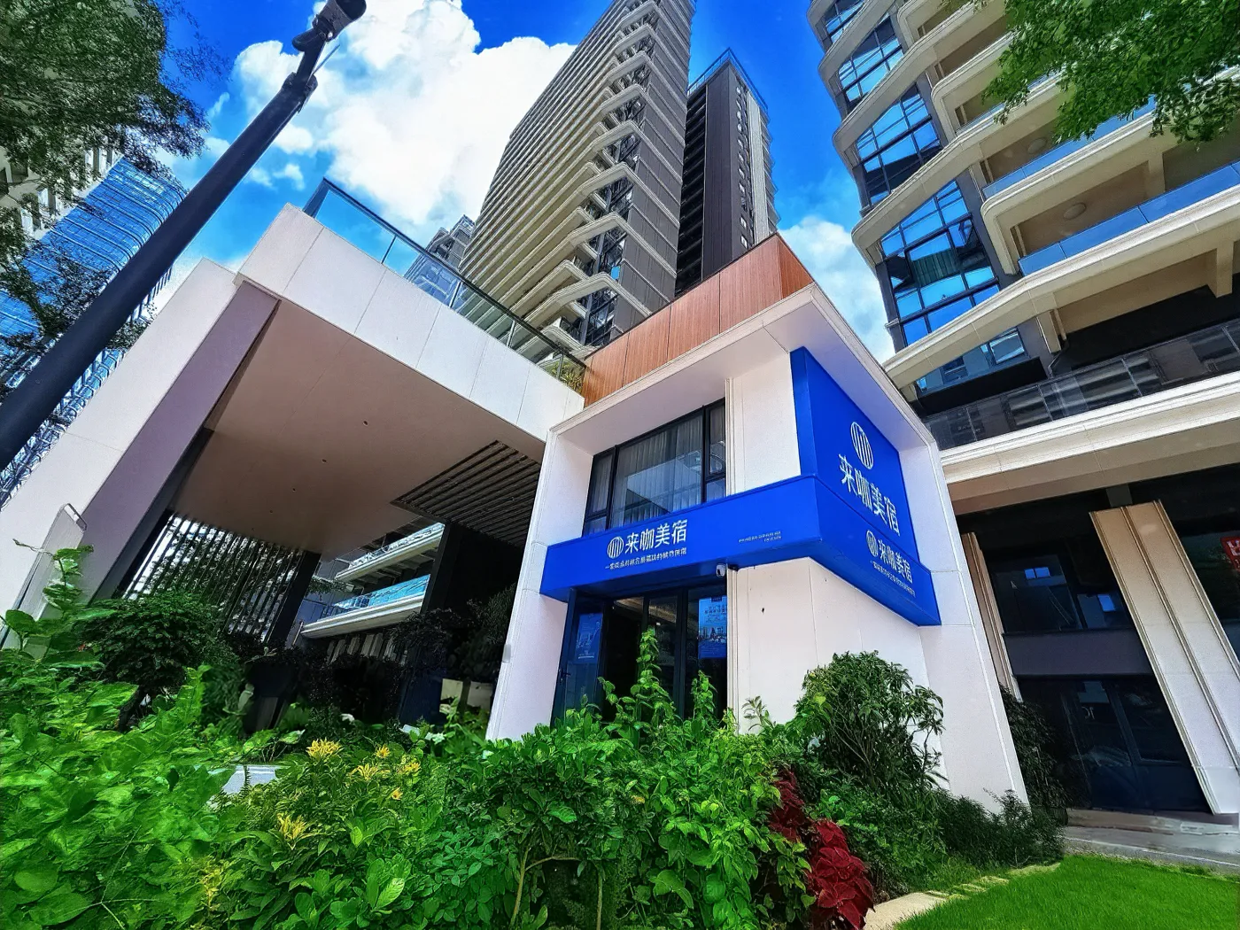 来咖美宿中粮大悦城店 门店门头实拍，蓝色来咖美宿招牌与沿街商铺入口